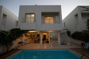 a villa with a swimming pool in front of a house at Jasmine Sea Front Villa in Protaras