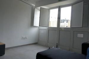 a room with white walls and windows and a bed at Urban front - Walking distance from paceville and st george bay beach in Is-Swieqi