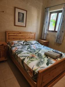 Schlafzimmer mit einem Bett mit einem Holzrahmen und einem Fenster in der Unterkunft Exclusive Pool with your own views with 3 bedrooms and 4 bathrooms in Gozo in Għajn il-Kbira