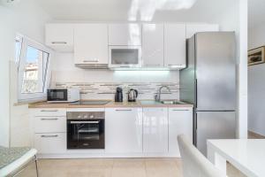 uma cozinha com armários brancos e um frigorífico de aço inoxidável em Villa Trebotić em Milna