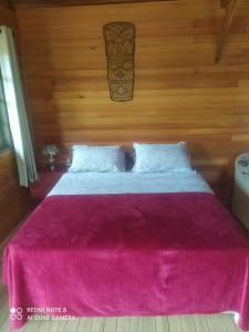 a bedroom with a pink bed with a wooden wall at Vila Sol Cabana in Lontras