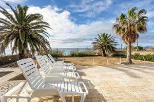 a row of white lounge chairs on the beach at Casa da Praia in Vila Baleira