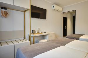 a bedroom with two beds and a desk and a tv at Duplo Charme Boutique Hotel in Lisbon