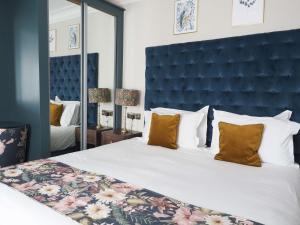a bedroom with a large bed with a large blue headboard at Hotel Collingwood BW Signature Collection in Bournemouth