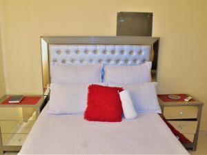 Cama con almohada roja y almohadas blancas en P Wake Guesthouse, en Opuwo