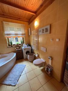 ein Badezimmer mit einer Badewanne, einem WC und einem Waschbecken in der Unterkunft Domek w Gaju in Gaj Grzmięca