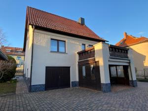 una casa blanca con garaje en una entrada en Charmantes Ferienhaus Gernrode/ Harz, Balkon, Grill, 2 Schlafzimmer, en Quedlinburg