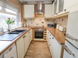 a kitchen with white cabinets and a sink and a window at Fellend House in Bishop Auckland