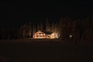 une maison éclairée la nuit dans les bois dans l'établissement Rukan Salonki Chalets, à Ruka