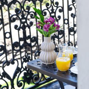 une table avec un vase de fleurs et du jus d'orange dans l'établissement TIFLIS OPERA Aparthotel, à Tbilissi