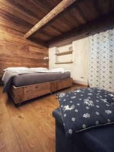 a bedroom with a bed and a couch and wooden ceilings at AMELU' LOCAZIONI TURISTICHE in Ostana
