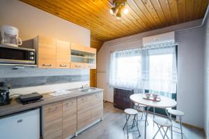 cocina con mesa, sillas y ventana en Csini vendégház, en Balatonföldvár