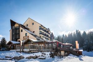 a ski lodge in the snow with the sun at Hôtel Chalet Margot in Le Dévoluy