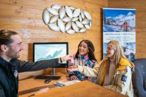 Ein Mann, der einer Frau am Tisch ein Glas Wein übergibt. in der Unterkunft SUNWEB Hôtel Chalet Margot in Le Dévoluy