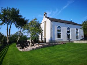 Knocknacarry的住宿－Mullarts Church -The Glendun Apartment，一座古老的白色教堂,有草地庭院