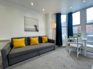 uma sala de estar com um sofá cinzento e almofadas amarelas em Stylish Modern Apartment For Up To 4 Nr CityCentre em Cardiff