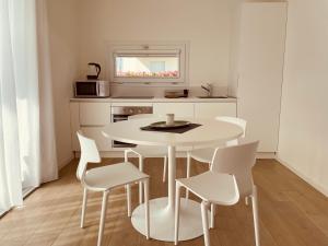 a white kitchen with a white table and chairs at JESOLO GROUND FLOOR FLAT WITH POOL - 2 family apartments in Lido di Jesolo