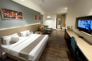 Hotel Classic Residency في كالكا: غرفة فندقية بسرير كبير وتلفزيون بشاشة مسطحة