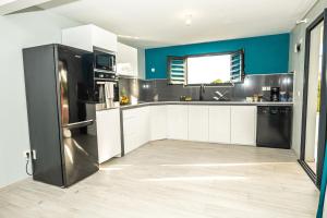a kitchen with white cabinets and a black refrigerator at VT cottage in Rivière-Pilote