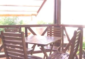 - une table en bois et 2 chaises sur une terrasse couverte dans l'établissement Bungalows les deux chênes, à La Plaine des Cafres