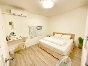 ein weißes Schlafzimmer mit einem Bett und einem Schreibtisch in der Unterkunft 清清長屋包棟民宿 Ding House in Altstadt von Hengchun
