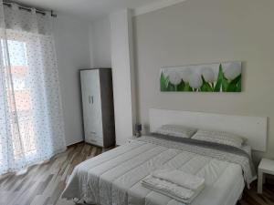 a white bedroom with a bed and a refrigerator at Onicasa Vacanza in Arma di Taggia