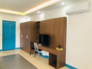 a room with a desk with a television and a blue door at An's Family Homestay Hoi An - 5mins walk to Hoi An Ancient Town in Hoi An