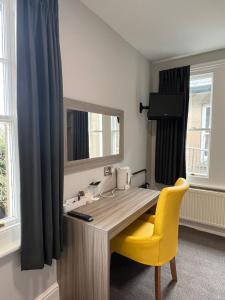 a desk with a yellow chair and a mirror at St Andrews Town Hotel in Droitwich