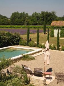 a pool with an umbrella and a chair and a table at Une chapelle en soie in Taulignan
