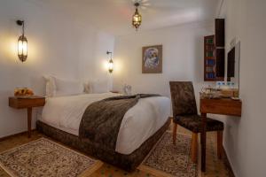 een slaapkamer met een bed, een bureau en een stoel bij riad dar nejma & Spa in Marrakesh