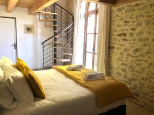 um quarto com uma cama com lençóis amarelos e uma janela em Une chapelle en soie em Taulignan