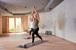 twee vrouwen die yoga doen in een yogaruimte bij Hotel Alte Post in Fieberbrunn