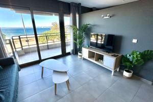 Roses Apartments - Marivent (2rooms) Vistas frontales al mar في روساس: غرفة معيشة مع أريكة وتلفزيون وطاولة