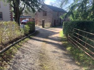 a dirt road next to a house with a fence at Brookfield House Warcop in Warcop