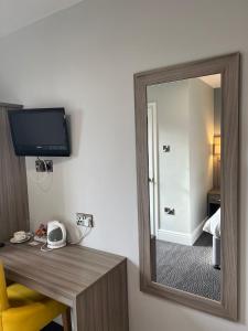 a mirror in a hotel room with a desk with a phone at St Andrews Town Hotel in Droitwich