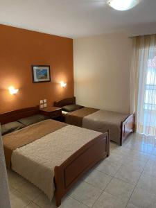 a hotel room with two beds and a window at Hotel Manos in Paralia Katerinis