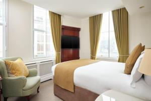um quarto de hotel com uma cama e uma cadeira em The Prime London Hotel em Londres