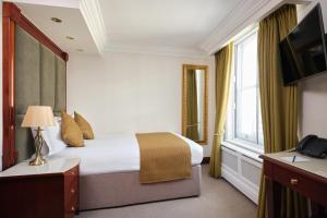 um quarto de hotel com uma cama e uma janela em The Prime London Hotel em Londres