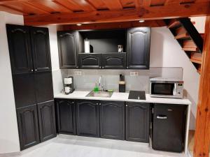 a kitchen with black cabinets and a sink and a microwave at SQUARE 16 - Absolutely Central Location in Szombathely