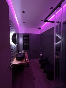 een badkamer met paarse verlichting en 2 wastafels en toiletten bij La balena bianca house in Bagni San Filippo
