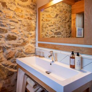 a bathroom with a sink and a stone wall at Hotel Boutique Niu de Sol - Designed for Adults in Palau-Saverdera