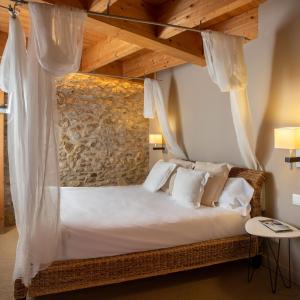 a bedroom with a canopy bed with white pillows at Hotel Boutique Niu de Sol - Designed for Adults in Palau-Saverdera