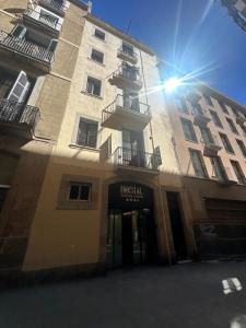 a tall building with the sun shining on it at Central and Basic Drassanes HOSTEL in Barcelona