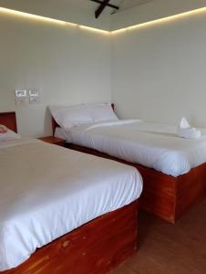 two beds in a room with white sheets at CHEENI HILL RESORTS in Kanthalloor