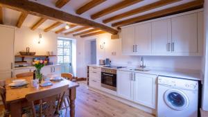 a kitchen with a table and a washer and dryer at Hope Cottage in Naunton