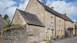 an old stone building on the side of a street at Hope Cottage in Naunton