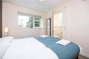 ein weißes Schlafzimmer mit einem großen Bett und einem Fenster in der Unterkunft Errigal House, Eglington Road, Donnybrook, Dublin 4 -By Resify in Dublin