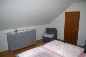 um quarto com uma cama, uma cómoda e uma cadeira em Ferienwohnung Friedrichswalde em Bahretal