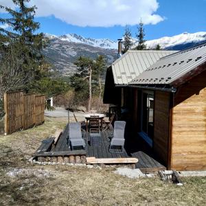 a cabin with a table and chairs on a deck at Chalet paisible 6 personnes in Uvernet