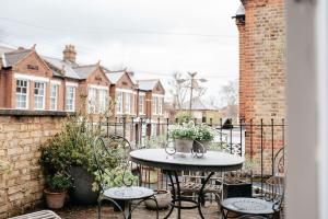 een patio met een tafel en stoelen en een hek bij 3 Bedroom House in Kew Gardens in Richmond